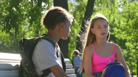 Multicultural teenagers with backpack talking on bench outdoors Stock Footage 157963330
