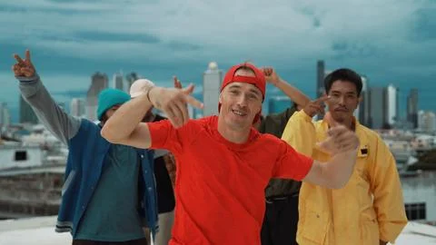 Multicultural teenagers dancing while looking at camera on rooftop. Endeavor. Stock Photos