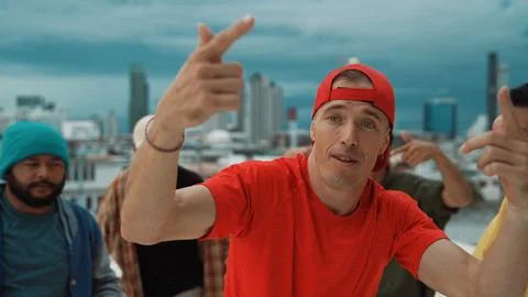 Multicultural teenagers dancing while looking at camera on rooftop. Endeavor. Stock Photos