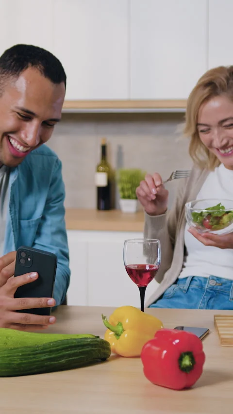 Multicultural young family using phone in modern kitchen. Man showing something  Stock Footage 328317710
