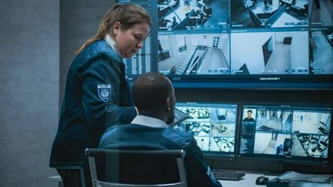 Multiethnic CCTV operators control security cameras on computer and tablet Stock Photos