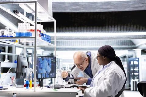 Multiethnic chemists doing a microscopy experiment in research lab Stock Photos
