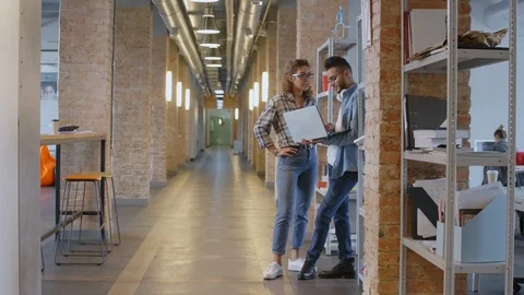 Multiethnic Colleagues Using Laptop and Talking in Hallway Stock Footage 126132897