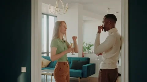 A multiethnic couple chatting and drinking champagne at home party Stock Footage 220723097