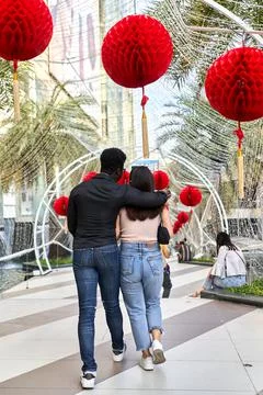 Multiethnic couple embracing while walking in a shopping mall Stock Photos