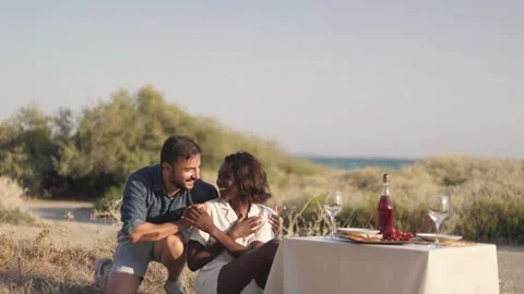 Multiethnic couple having surprise date with celebration picnic on beach Stock Footage 270248543