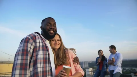 Multiethnic couple hugging and looking at camera, spending time at roof party Stock-Footage 117215650
