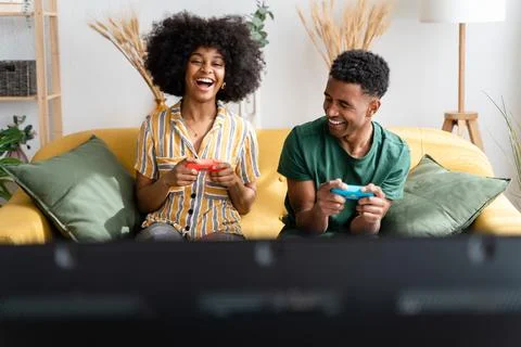 Multiethnic couple playing videogames on sofa Stock Photos