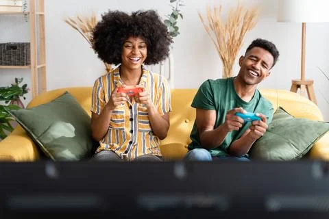 Multiethnic couple playing videogames on sofa Stock Photos