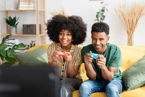 Multiethnic couple playing videogames on sofa Stock Photos