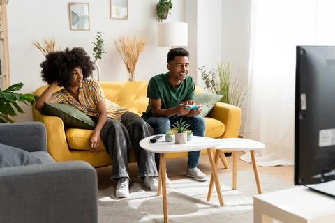 Multiethnic couple playing videogames on sofa Stock Photos