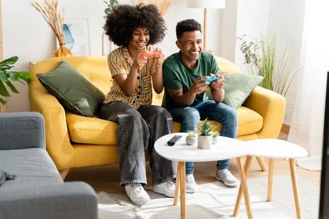Multiethnic couple playing videogames on sofa Stock Photos