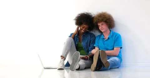 Multiethnic couple sitting on the floor using a laptop and tablet 스톡 사진