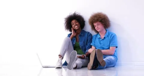 Multiethnic couple sitting on the floor using a laptop and tablet 스톡 사진
