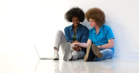 Multiethnic couple sitting on the floor using a laptop and tablet 写真素材