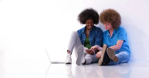 Multiethnic couple sitting on the floor using a laptop and tablet 스톡 사진