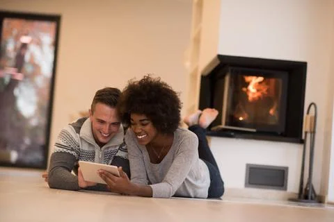 Multiethnic couple using tablet computer on the floor beautiful young mult... Stock Photos