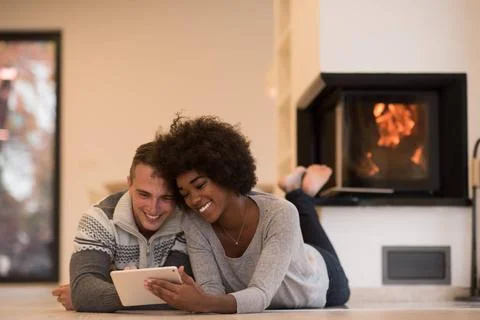 Multiethnic couple using tablet computer on the floor beautiful young mult... Stock Photos