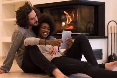 Multiethnic couple using tablet computer on the floor beautiful young mult... Stock Photos