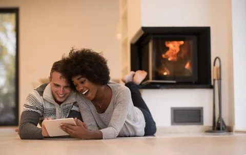 Multiethnic couple using tablet computer on the floor beautiful young mult... Stock Photos