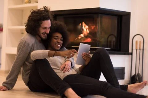 Multiethnic couple using tablet computer on the floor beautiful young mult... Stock Photos
