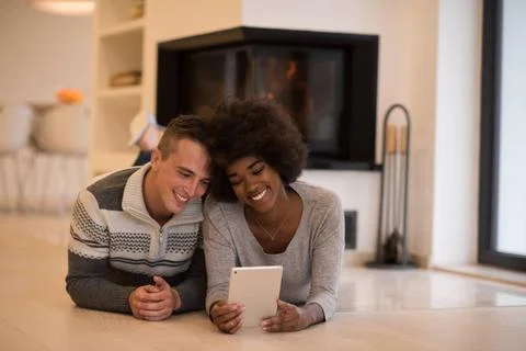 Multiethnic couple using tablet computer on the floor beautiful young mult... Stock Photos