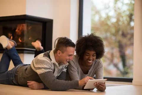 Multiethnic couple using tablet computer on the floor beautiful young mult... Stock Photos