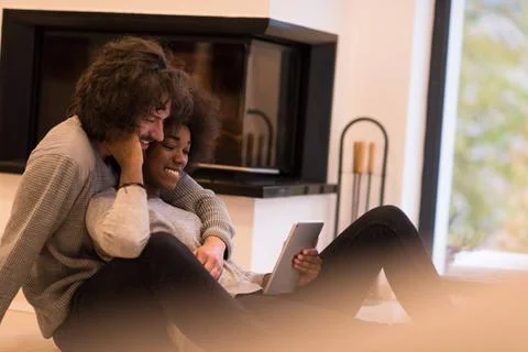 Multiethnic couple using tablet computer on the floor beautiful young mult... Stock Photos