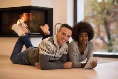 Multiethnic couple using tablet computer on the floor beautiful young mult... Stock Photos