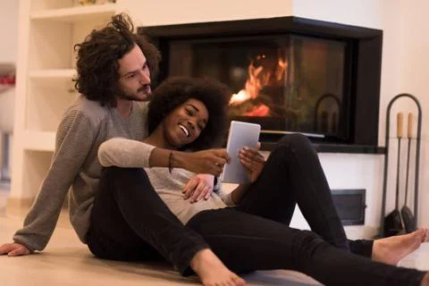 Multiethnic couple using tablet computer on the floor beautiful young mult... Stock Photos