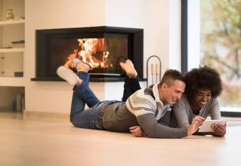 Multiethnic couple using tablet computer on the floor beautiful young mult... Stock Photos