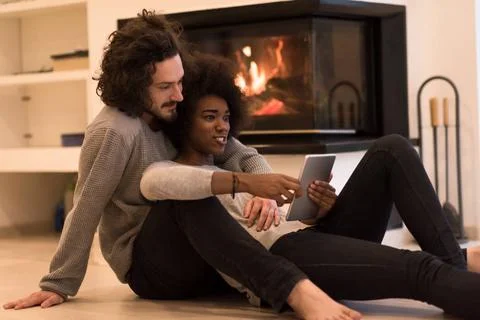 Multiethnic couple using tablet computer on the floor beautiful young mult... Stock Photos