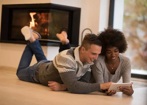 Multiethnic couple using tablet computer on the floor beautiful young mult... Stock Photos