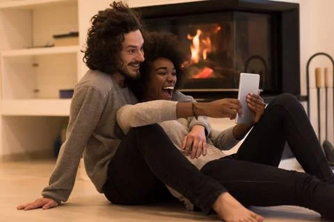 Multiethnic couple using tablet computer on the floor beautiful young mult... Stock Photos
