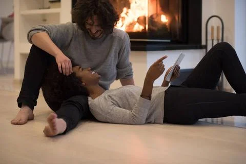 Multiethnic couple using tablet computer on the floor beautiful young mult... Stock Photos
