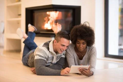 Multiethnic couple using tablet computer on the floor beautiful young mult... Stock Photos