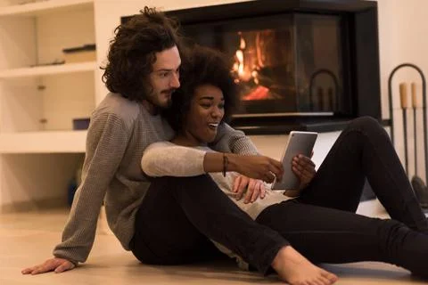 Multiethnic couple using tablet computer on the floor beautiful young mult... Stock Photos