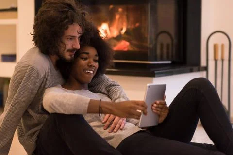 Multiethnic couple using tablet computer on the floor beautiful young mult... Stock Photos