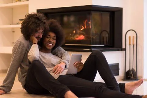 Multiethnic couple using tablet computer on the floor beautiful young mult... Stock Photos