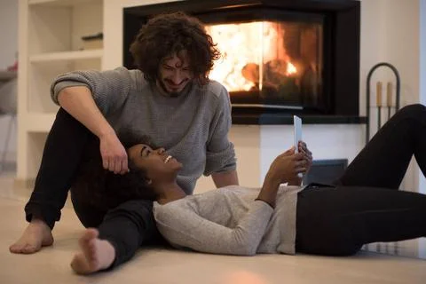 Multiethnic couple using tablet computer on the floor beautiful young mult... Stock Photos