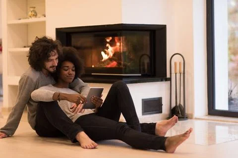 Multiethnic couple using tablet computer on the floor beautiful young mult... Stock Photos