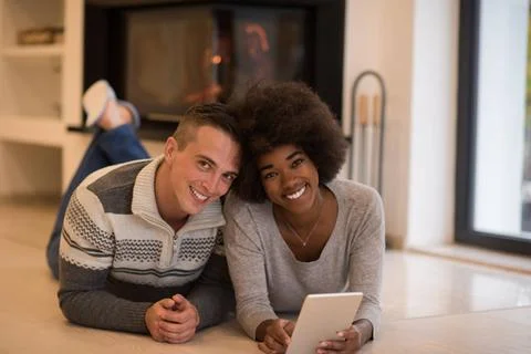 Multiethnic couple using tablet computer on the floor beautiful young mult... Stock Photos