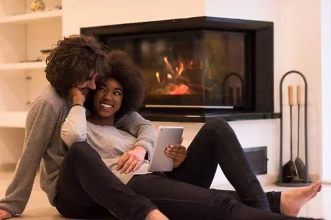 Multiethnic couple using tablet computer on the floor beautiful young mult... Stock Photos