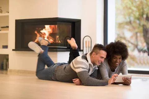 Multiethnic couple using tablet computer on the floor beautiful young mult... Stock Photos