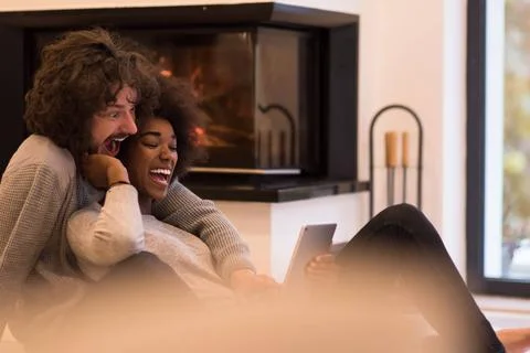 Multiethnic couple using tablet computer on the floor beautiful young mult... Stock Photos