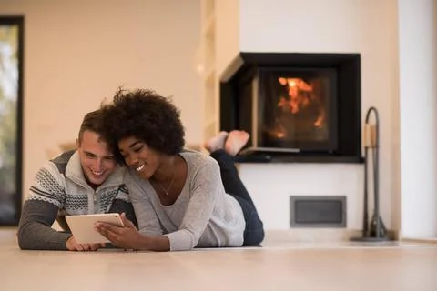 Multiethnic couple using tablet computer on the floor beautiful young mult... Stock Photos