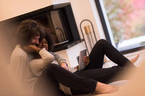 Multiethnic couple using tablet computer on the floor beautiful young mult... Stock Photos