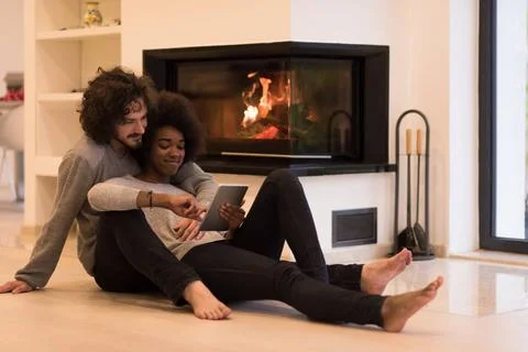 Multiethnic couple using tablet computer on the floor beautiful young mult... Stock Photos