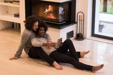 Multiethnic couple using tablet computer on the floor beautiful young mult... Stock Photos
