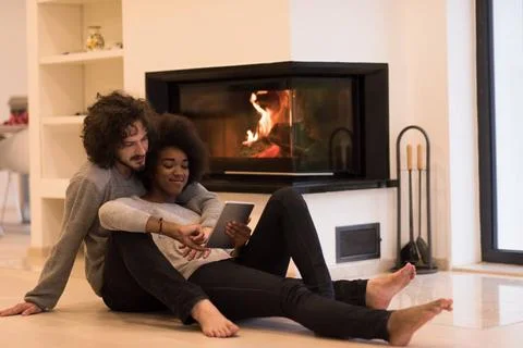 Multiethnic couple using tablet computer on the floor beautiful young mult... Stock Photos